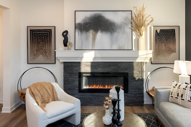 sitting room with a tiled fireplace and dark wood-type flooring