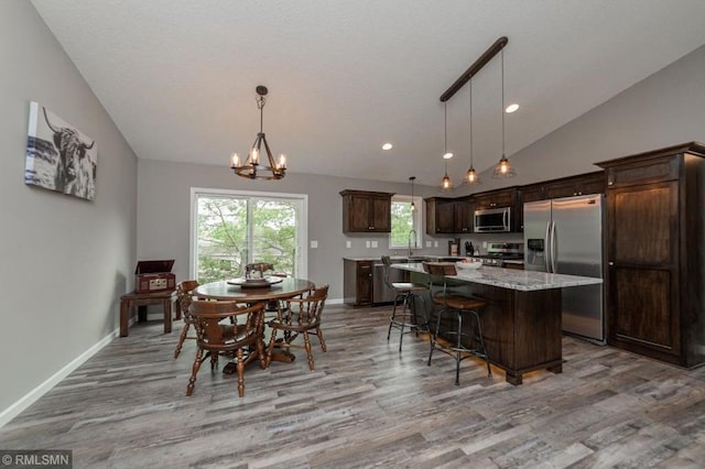 dining room featuring vaulted ceiling, an inviting chandelier, light hardwood / wood-style flooring, and sink