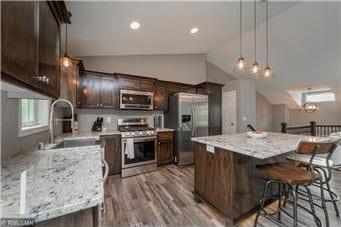 kitchen featuring light stone countertops, stainless steel appliances, lofted ceiling, and sink