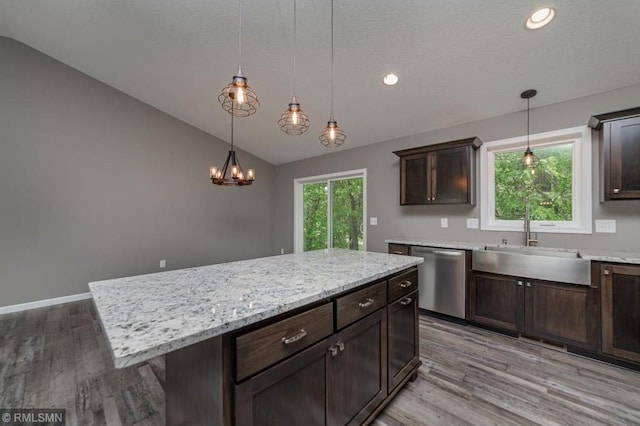 kitchen featuring stainless steel dishwasher, vaulted ceiling, decorative light fixtures, light hardwood / wood-style flooring, and a center island