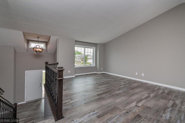 interior space with dark hardwood / wood-style flooring, lofted ceiling, a textured ceiling, and an inviting chandelier