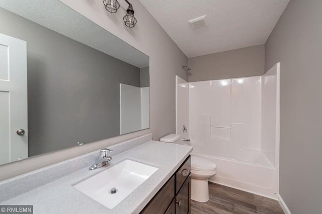 full bathroom featuring wood-type flooring, a textured ceiling,  shower combination, toilet, and vanity