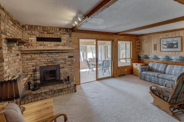 living room with beam ceiling, a fireplace, a textured ceiling, and light colored carpet