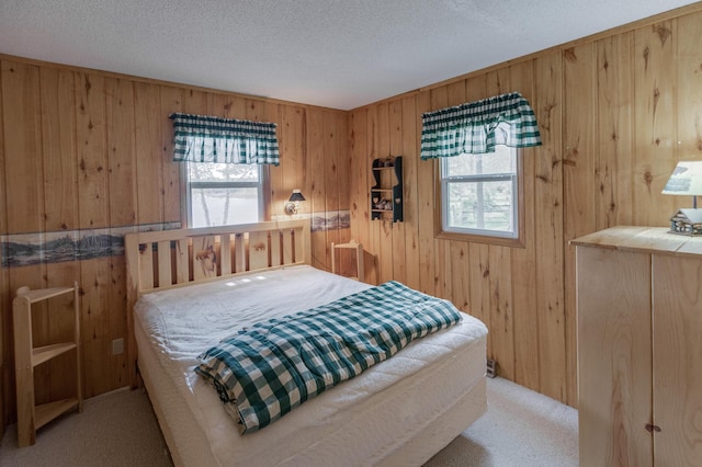 carpeted bedroom with wood walls and a textured ceiling