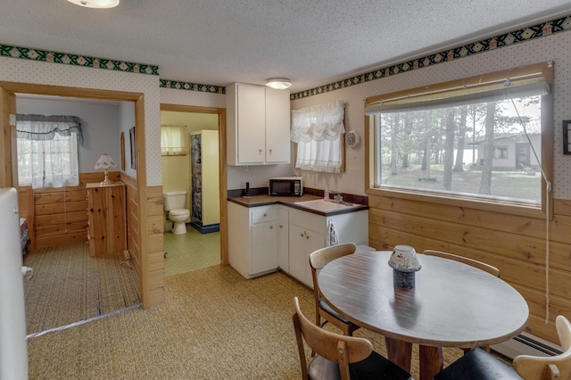 kitchen with white cabinetry, sink, a baseboard heating unit, a textured ceiling, and light tile patterned floors