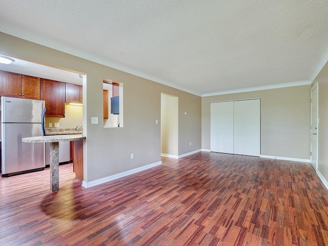 unfurnished living room with a textured ceiling and dark wood-type flooring