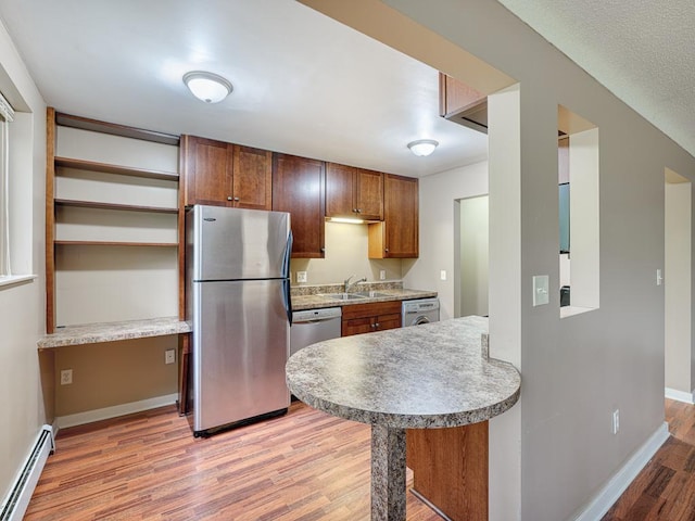 kitchen with sink, baseboard heating, stainless steel appliances, and light hardwood / wood-style flooring