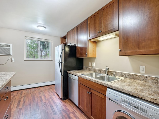 kitchen featuring stainless steel dishwasher, a baseboard heating unit, sink, washer / dryer, and dark hardwood / wood-style floors