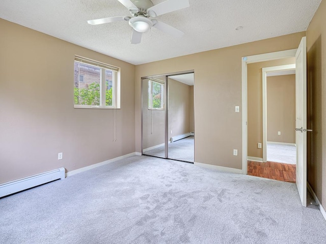 unfurnished bedroom featuring light carpet, a textured ceiling, ceiling fan, a baseboard heating unit, and a closet