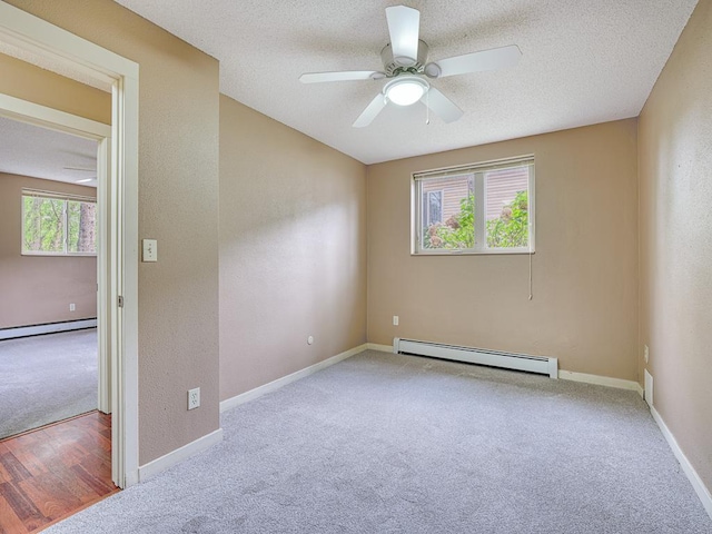 carpeted spare room with baseboard heating, ceiling fan, plenty of natural light, and a textured ceiling