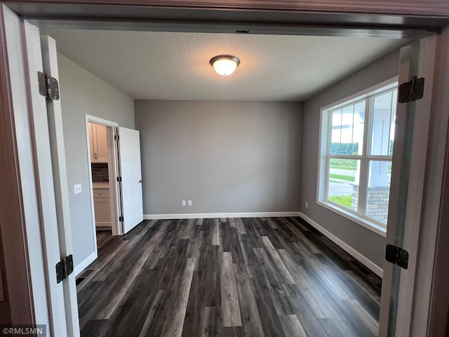 unfurnished room with a textured ceiling and dark hardwood / wood-style floors