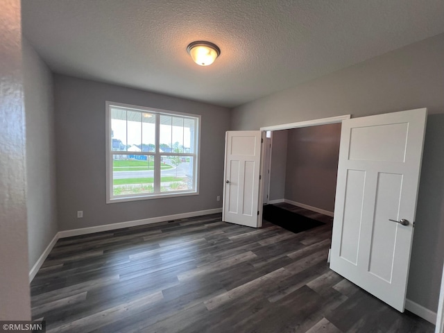 unfurnished bedroom with a textured ceiling and dark hardwood / wood-style floors