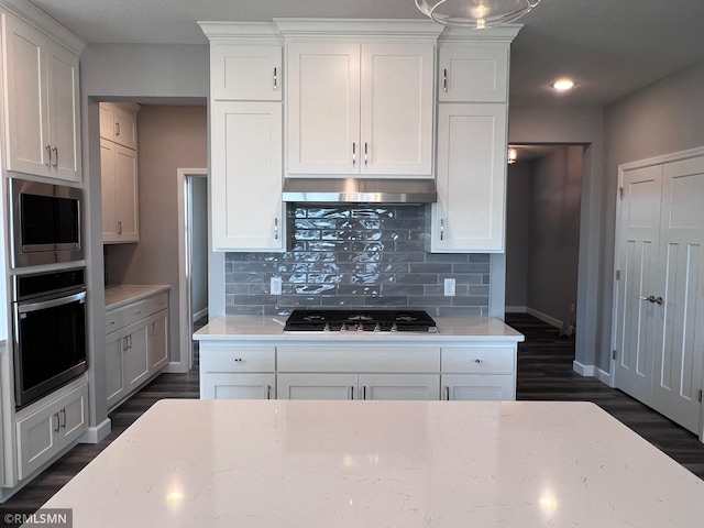 kitchen with backsplash, dark hardwood / wood-style flooring, stainless steel appliances, and white cabinets