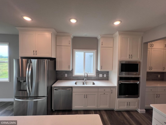 kitchen with decorative backsplash, white cabinetry, sink, and stainless steel appliances