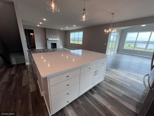 kitchen with white cabinets, dark wood-type flooring, a center island, and a fireplace