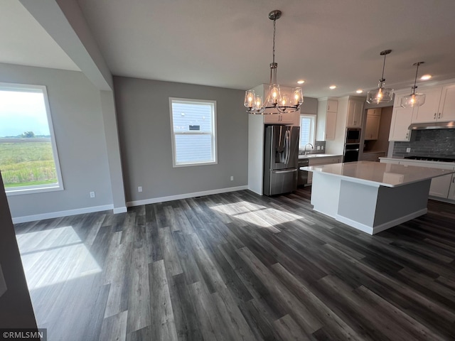 kitchen featuring decorative light fixtures, stainless steel fridge, white cabinetry, and a kitchen island