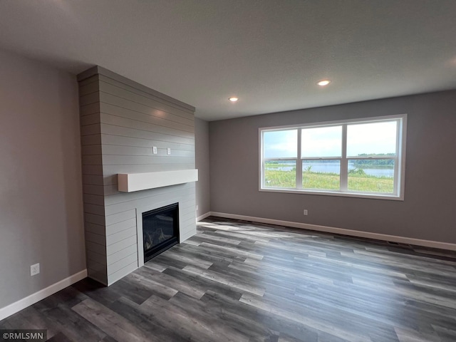 unfurnished living room with dark hardwood / wood-style floors, a textured ceiling, and a large fireplace