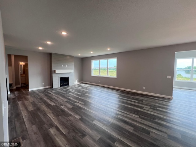 unfurnished living room featuring a textured ceiling, dark hardwood / wood-style flooring, and a large fireplace