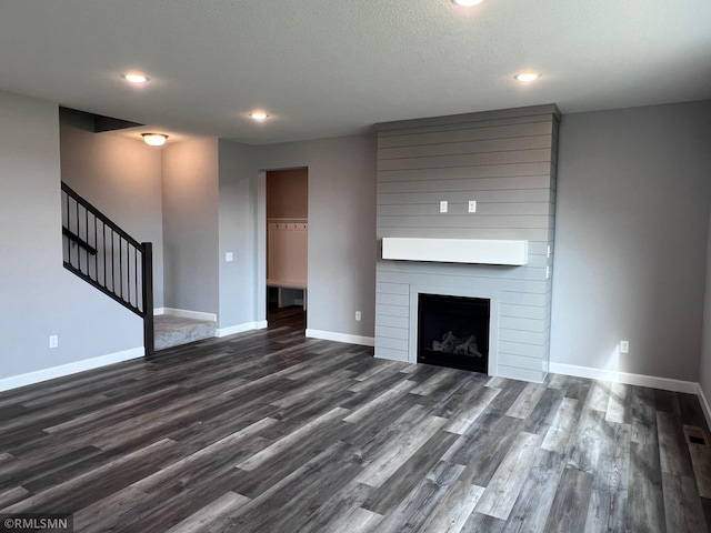 unfurnished living room with a textured ceiling, a fireplace, and dark hardwood / wood-style flooring