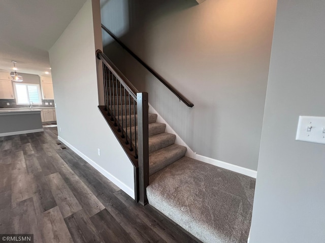 staircase with hardwood / wood-style flooring and sink