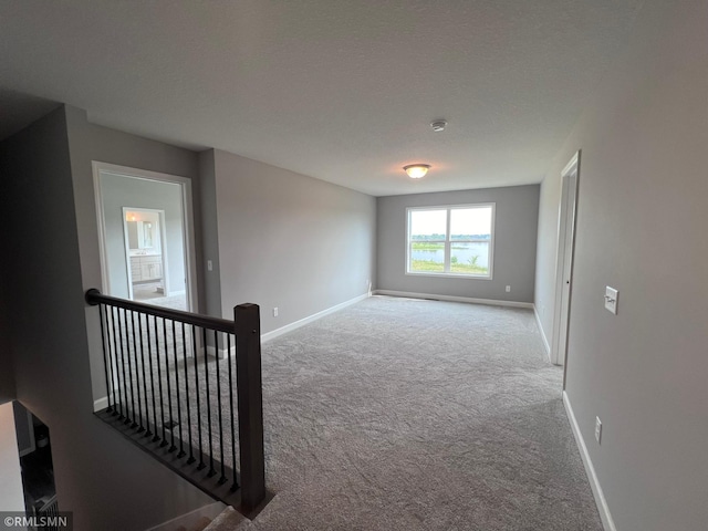 empty room with a textured ceiling and light colored carpet