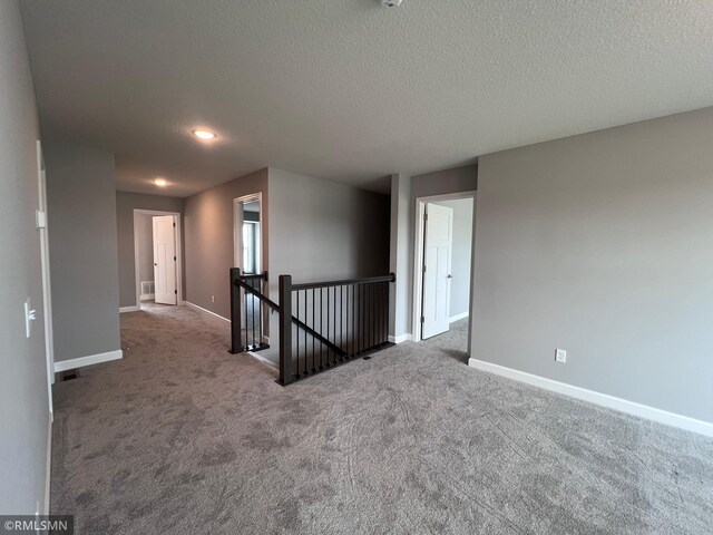 empty room with a textured ceiling and carpet flooring