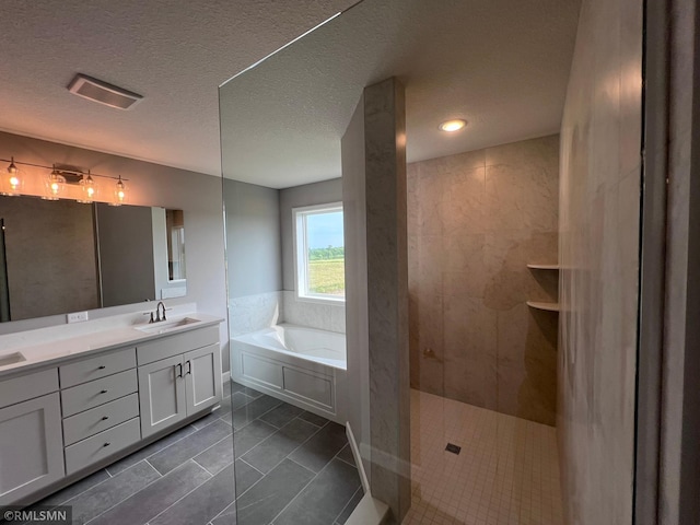 bathroom with plus walk in shower, tile patterned flooring, a textured ceiling, and vanity