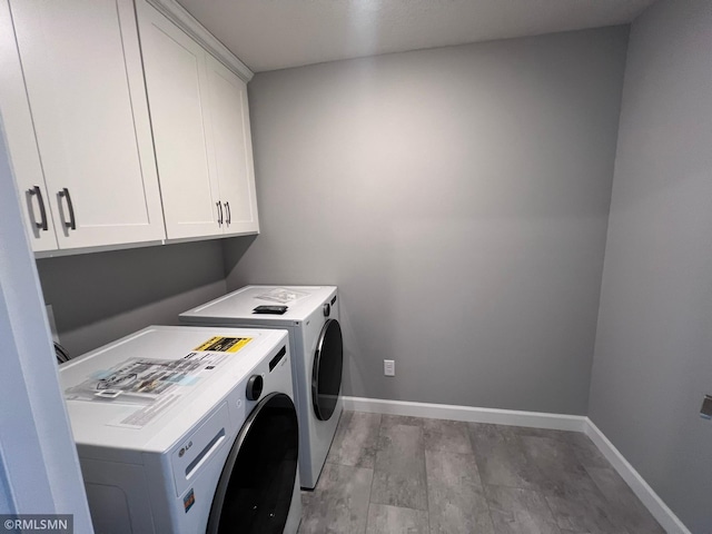 washroom with cabinets, hardwood / wood-style flooring, and washing machine and clothes dryer