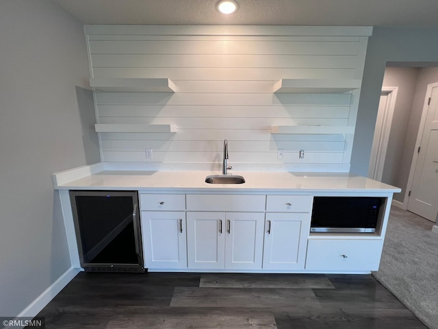 kitchen featuring white cabinetry, a textured ceiling, dark wood-type flooring, and sink