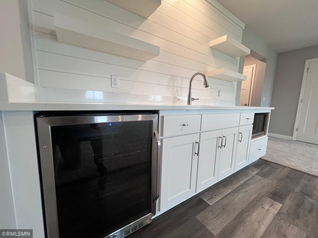 kitchen with beverage cooler, dark wood-type flooring, and white cabinetry