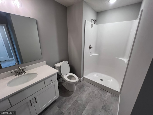 bathroom with walk in shower, vanity, and toilet