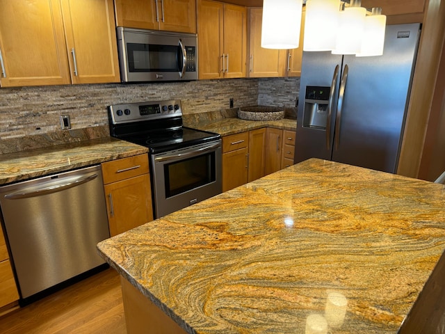 kitchen featuring appliances with stainless steel finishes, hardwood / wood-style flooring, tasteful backsplash, and light stone countertops