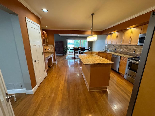 kitchen featuring light hardwood / wood-style floors, hanging light fixtures, stainless steel appliances, light stone counters, and tasteful backsplash