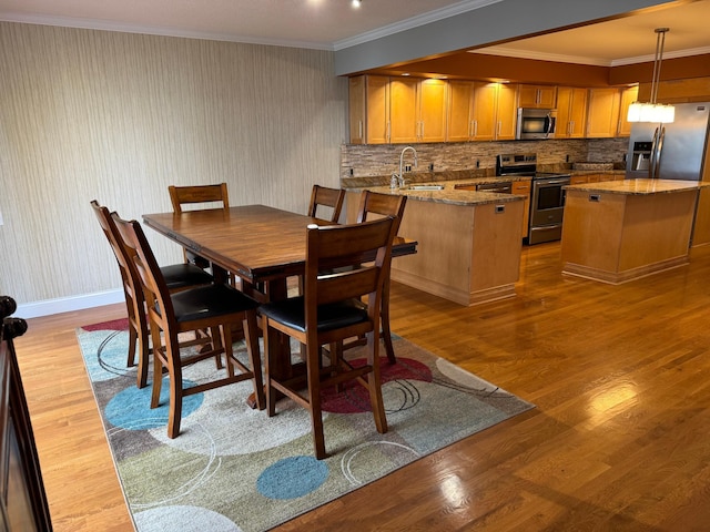 dining room featuring ornamental molding, light hardwood / wood-style flooring, and sink