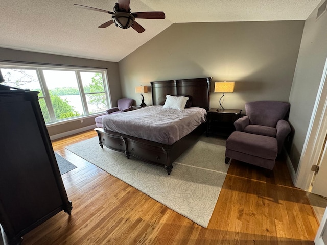 bedroom with ceiling fan, vaulted ceiling, a textured ceiling, and wood-type flooring