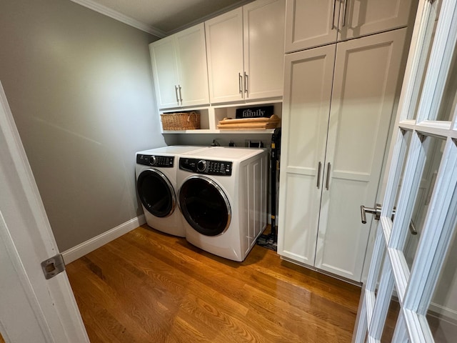 laundry room with crown molding, independent washer and dryer, hardwood / wood-style floors, and cabinets