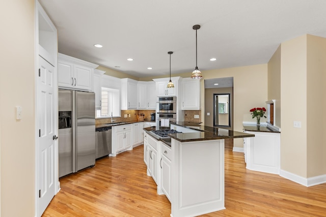 kitchen with a center island, white cabinets, light hardwood / wood-style floors, and appliances with stainless steel finishes