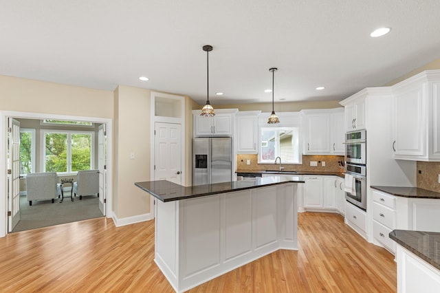 kitchen with a center island, stainless steel appliances, white cabinetry, and hanging light fixtures