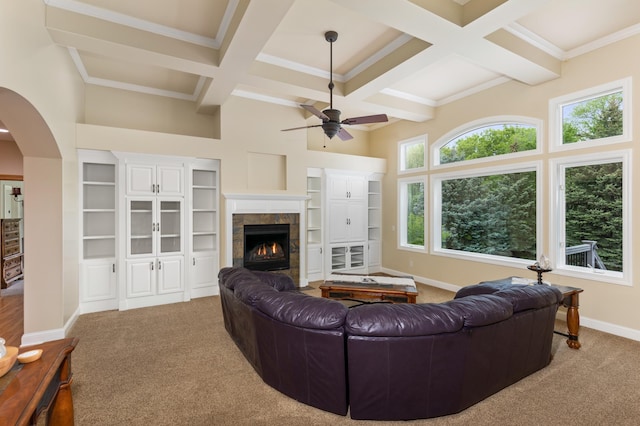 living room with a tile fireplace, coffered ceiling, crown molding, carpet flooring, and ceiling fan