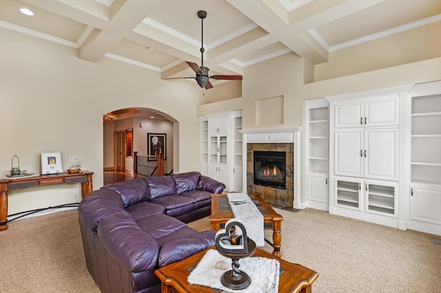 carpeted living room featuring coffered ceiling, ceiling fan, crown molding, beam ceiling, and a tiled fireplace