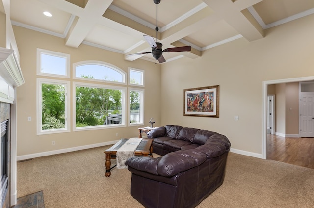 carpeted living room featuring beamed ceiling, ceiling fan, plenty of natural light, and a tiled fireplace