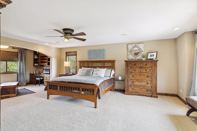 bedroom featuring ceiling fan, light colored carpet, and multiple windows