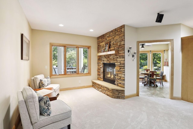 carpeted living room with a fireplace, ceiling fan, and plenty of natural light