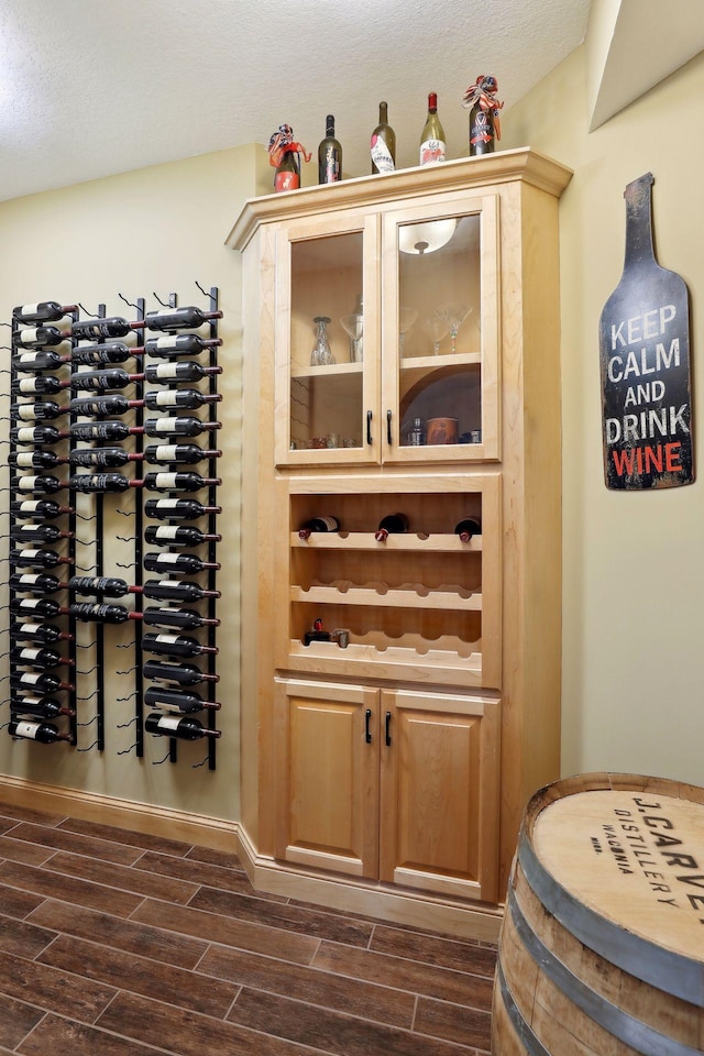 wine area featuring a textured ceiling and dark wood-type flooring