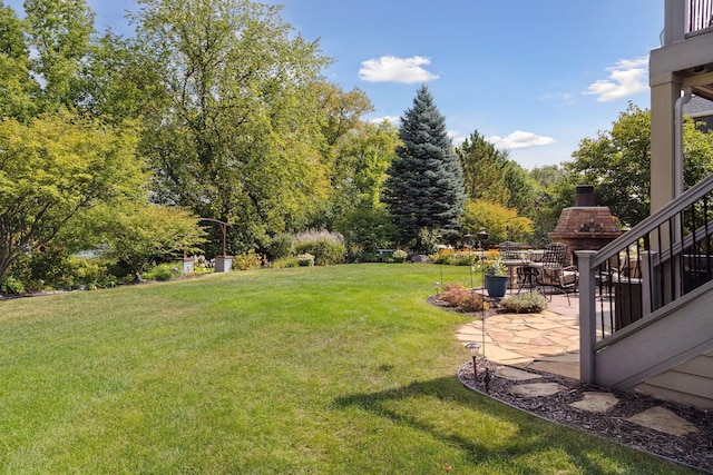 view of yard featuring a patio and an outdoor fireplace