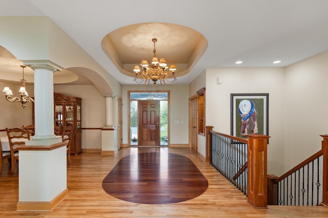 foyer entrance featuring light hardwood / wood-style flooring, a tray ceiling, and an inviting chandelier