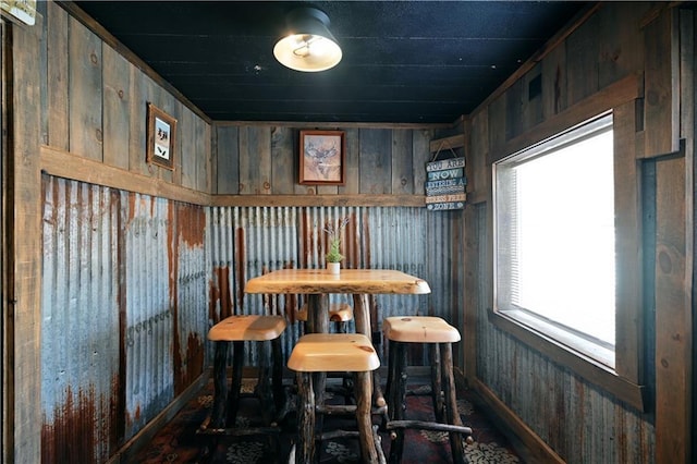 dining space with bar, a wealth of natural light, and wood walls