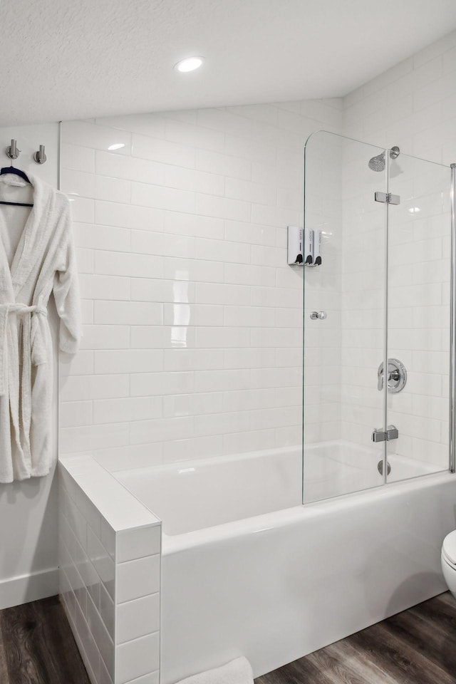 bathroom with tiled shower / bath combo, toilet, wood-type flooring, and lofted ceiling