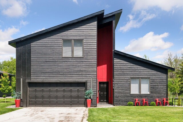 contemporary home featuring a garage and a front lawn