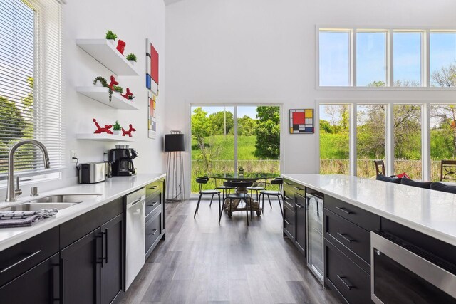 kitchen featuring dark hardwood / wood-style flooring, dishwasher, sink, and a towering ceiling